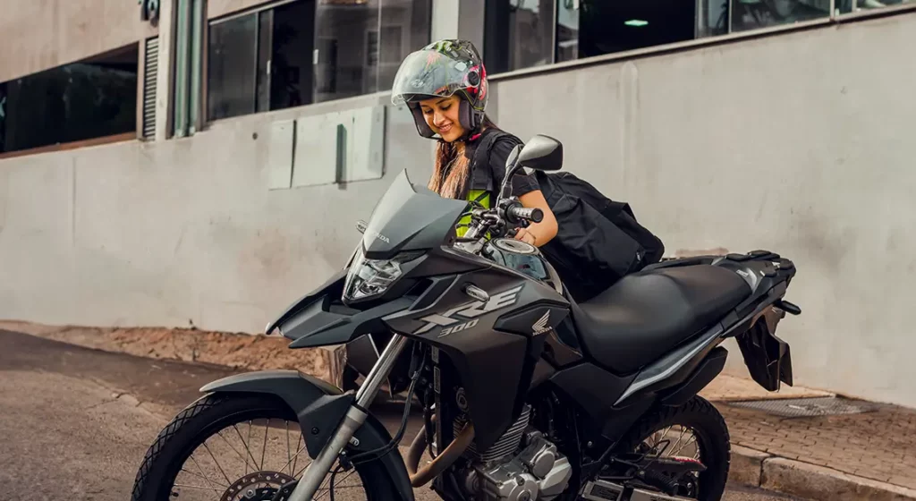 mulher ao lado de motocicleta representando como estacionar moto na subida